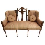 An Arts and Crafts mahogany and inlaid settee the pierced central back decorated with fruitwood