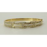 An 18ct gold diamond set bangle set with both brilliant cut and square step cut diamonds to an