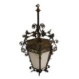 A wrought iron hall lantern with six opaque glass panels beneath a pierced scrolling foliate