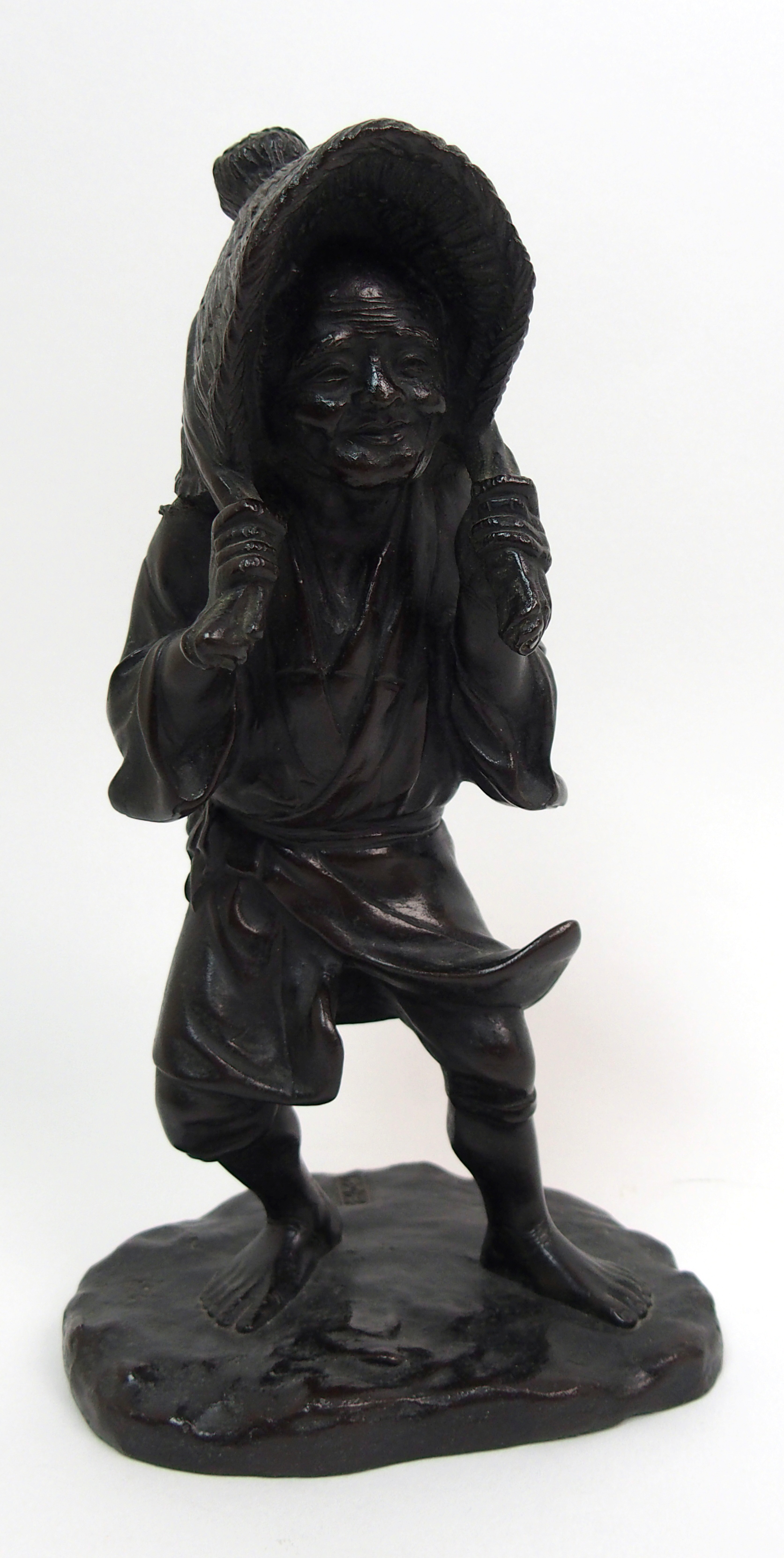 A Japanese bronze figure of a worker standing and holding straw hat around her head and on a mound - Image 2 of 8