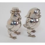 A pair of novelty white-metal pepperettes formed as chicks with hinged tops and detachable heads,