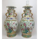 A pair of Canton famille rose two handled vases painted with panels of exotic birds, butterflies and