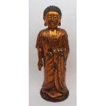 A Chinese gold lacquered bronze Buddhist figure standing and wearing flowing robes and on a circular