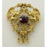 A Gothic revival garnet and diamond brooch twin griffins embrace a garnet and diamond set cluster to