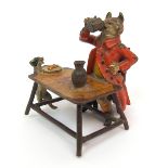 A cold painted bronze of a fox dressed in hunting coat, seated at a table drinking from a stein,