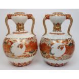 A pair of Kutani two handled vases painted with cranes on diaper bands beneath garlic necks joined