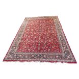 A red ground Eastern rug with all over floral design and a blue border, 580cm x 390cm