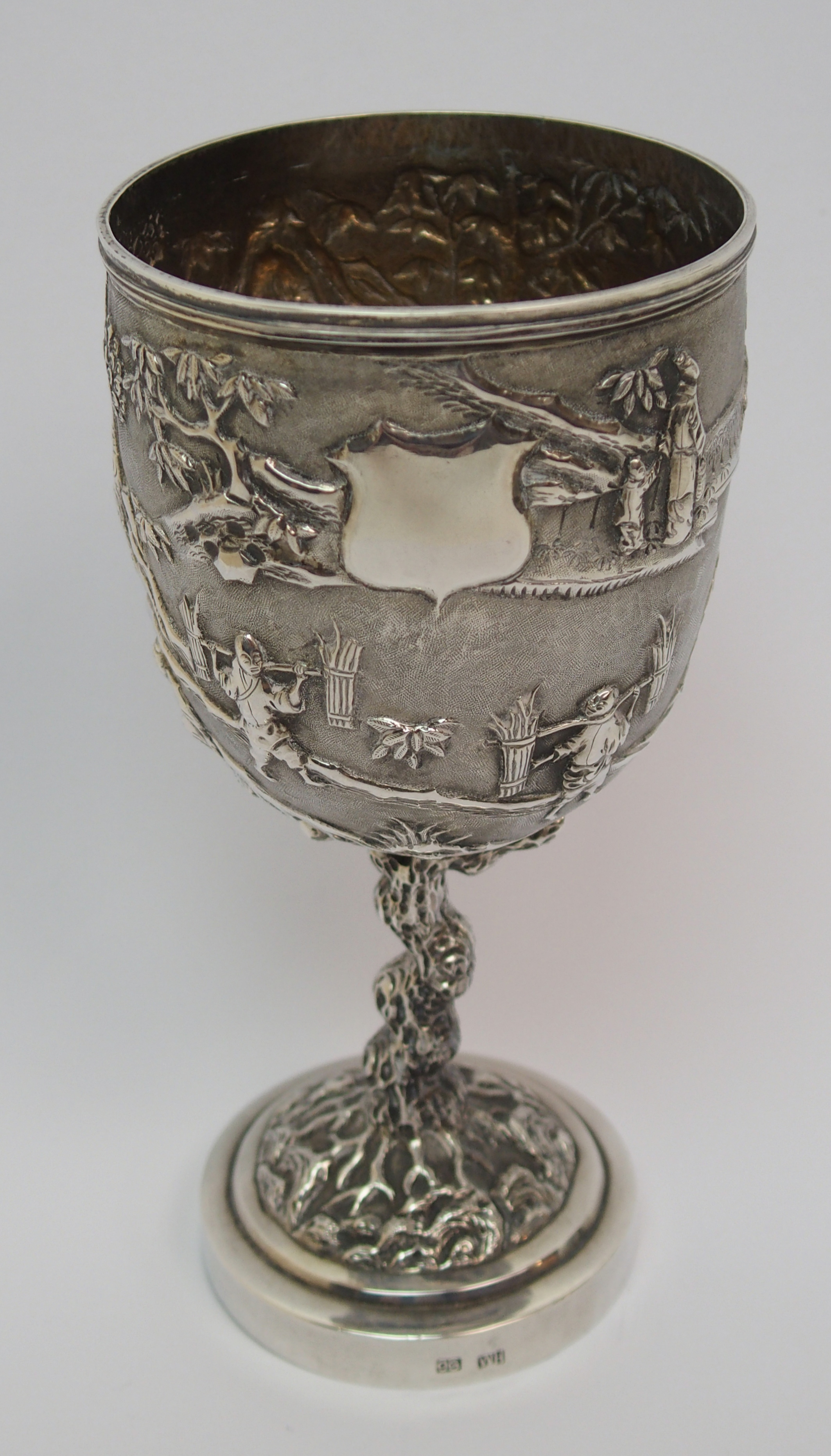 A Chinese Export silver goblet decorated with various figures in a mountainous landscape amongst