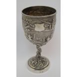 A Chinese Export silver goblet decorated with various figures in a mountainous landscape amongst