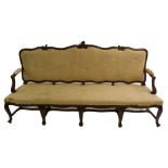 A Spanish walnut four seat settee with scrolling foliate frame above stuffed arms with scroll ends