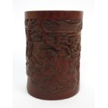 A Chinese bamboo spill vase carved with two figures seated beneath pine trees, beside a table set