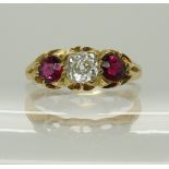 A bright yellow metal ruby and diamond ring in a scalloped setting, the central cushion cut