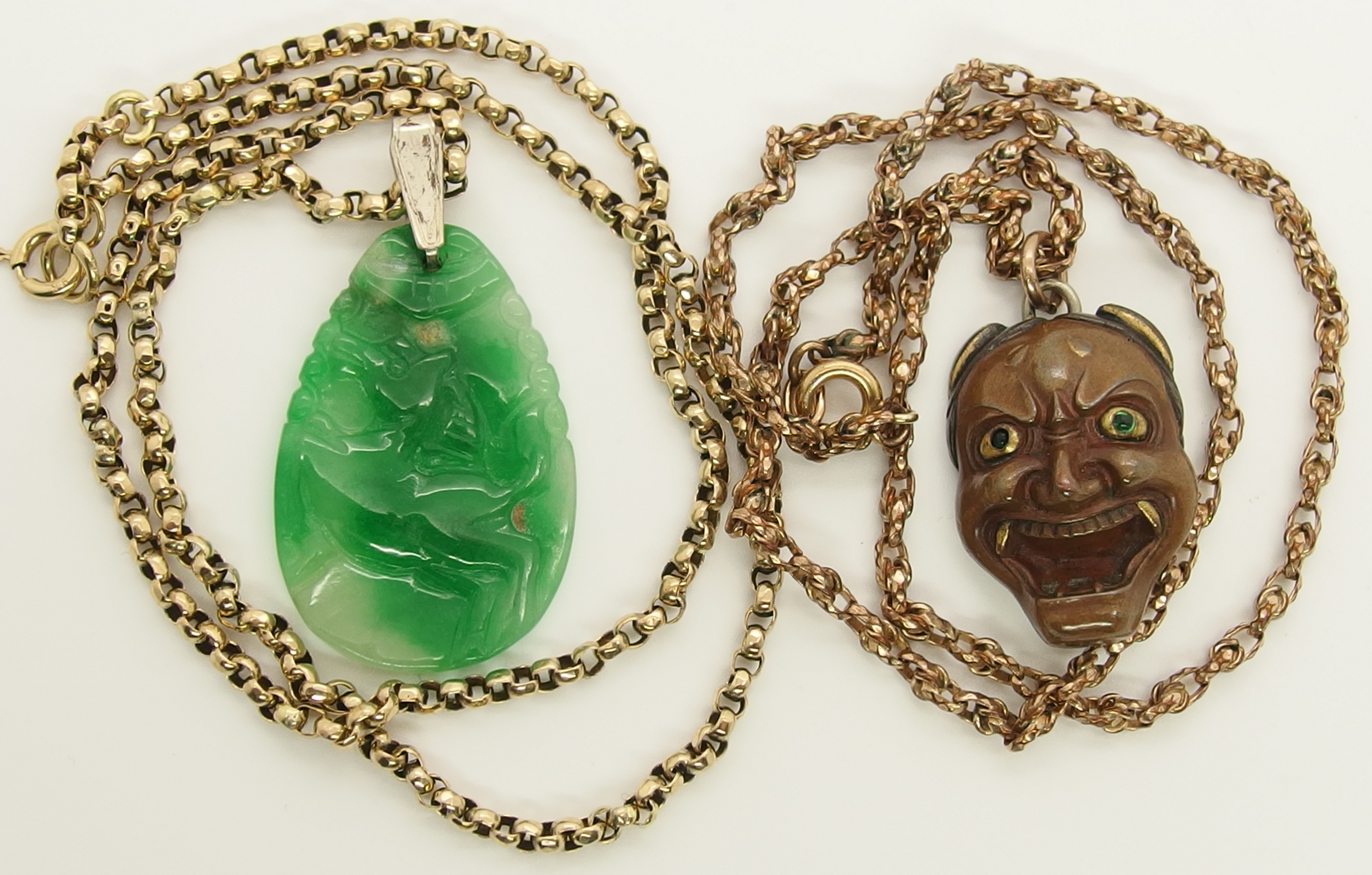 A Chinese green hardstone pendant and a Japanese demon mask pendant the hardstone pendant is