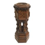 A Puginesque oak hexagonal baptismal font with inlaid medallions above six columns set with oak