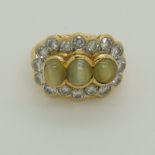 A bright yellow metal ring set with three cats eye chrysoberyls and diamonds to a tapered shouldered