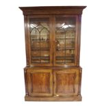 A Victorian mahogany two door bookcase enclosing shelves above a pair of panelled doors on a