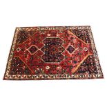 A red ground Bakhtier rug with vases and stylised birds and animals 202cm x 305cm