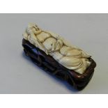 A Chinese ivory carving of Buddha, reclining, pierced and carved hardwood stand, 10.