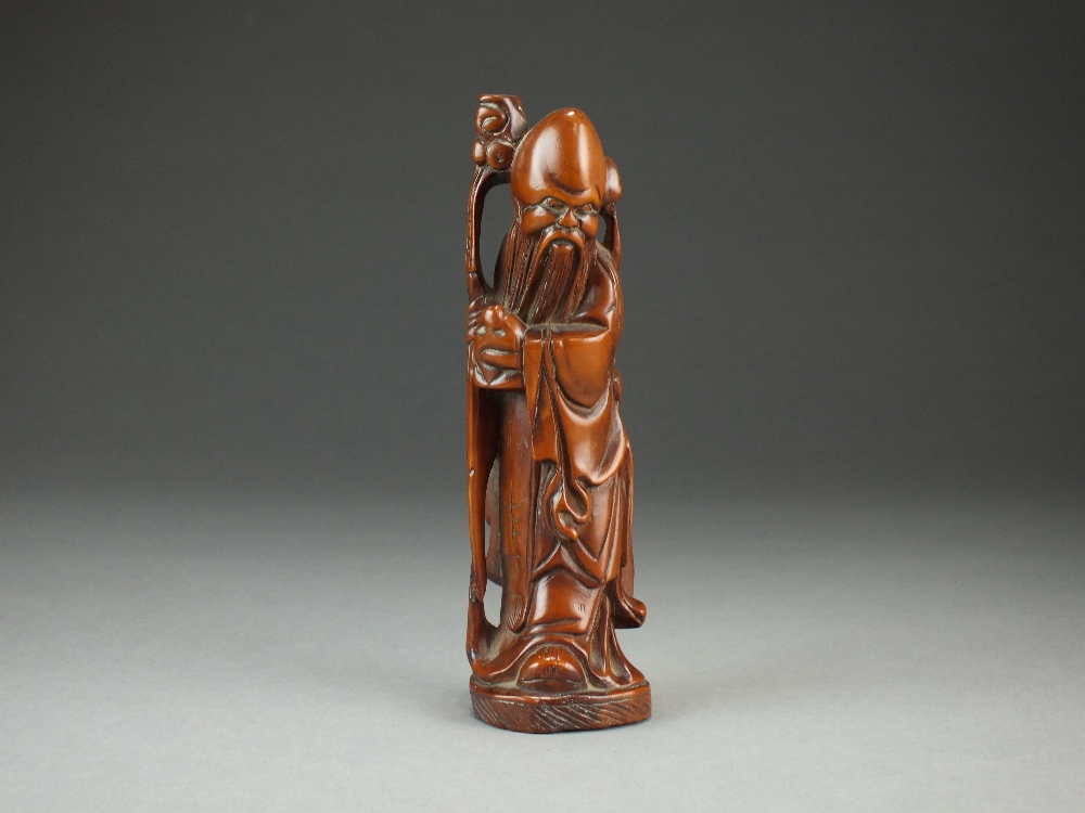 A Chinese rootwood figure of Shoulao, modelled standing and holding a staff and a peach, 18cm high.