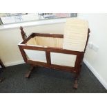 A 19th century style mahogany rocking crib with arched canopy and baluster turned supports