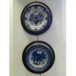 Two Dutch delft dishes painted in blue with stylised flowers and foliage and mounted in wood frames