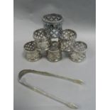 A set of six plated napkin rings together with a pair of silver sugar tongs