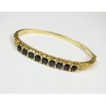 An 18ct gold diamond and sapphire set hinged bangle,