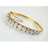 A late 19th century moonstone and ruby hinged bangle,