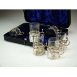 A cased set of six silver mounted glass tots, William Comyns, Birmingham 1897 & 1899,