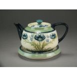 A Moorcroft Macintyre florian ware teapot, cover and stand tubelined with blue poppies,