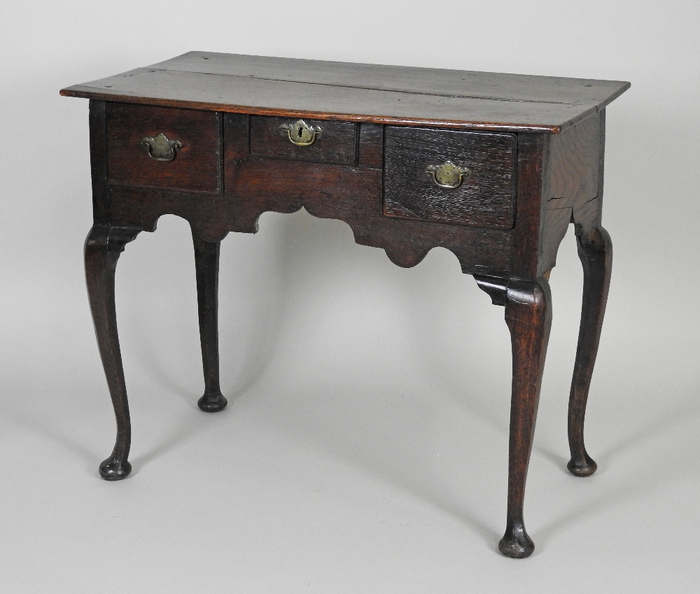 A mid 18th century oak lowboy the rectangular plank top over an arrangement of three short drawers
