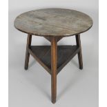 A George III oak and elm cricket table the circular three plank top on chamfered out-swept legs