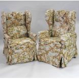 A pair of Edwardian oak winged armchairs, with swing out arms secured with brass catches,