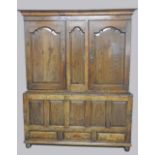 A George III oak livery cupboard the ogee moulded corners over a fixed fielded arch,