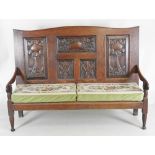 A 19th century oak settle the five panel back carved by Edwin Ridgeway between open down-swept arms