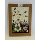 A Moorcroft trial plaque dated 3811 of wild flowers against a cream ground and in oak frame