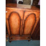 A Queen Anne style figured walnut veneer tallboy with two ribbed cabinet doors above a short drawer