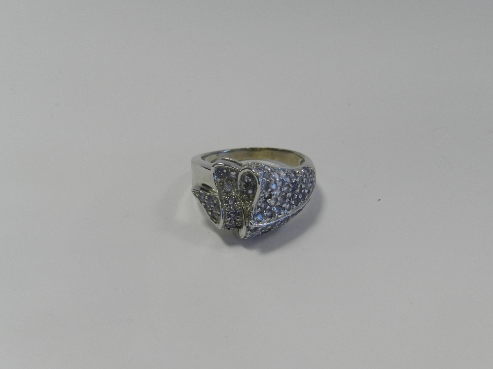 A 9ct white gold tanzanite set dress ring formed as a stylised ribbon