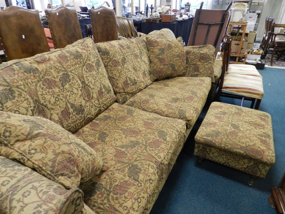 A modern sofa covered in a tapestry style material along with matching enclosed armchair en suite