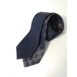 Two Gucci ties, one navy, one navy with gold Gucci logo pattern