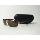 A pair of Prada sunglasses, brown metallic frame and black case
