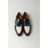 A pair of Gucci slip-on loafer with tassels and brogue detailing, black white and red leather plus
