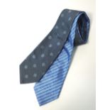 Two Gucci ties, one light blue with dark blue Gucci G pattern, one dark grey with Gucci G and spiral