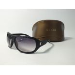 A pair of Gucci black wrap around sunglasses in push-together Gucci case and box