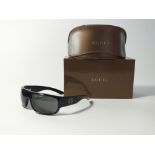 A pair of Gucci black sunglasses with arm Gucci G detail in push-together case