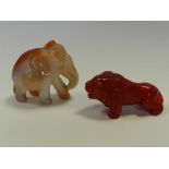 A carnelian agate style of an elephant and a red polished stone figure of a lion