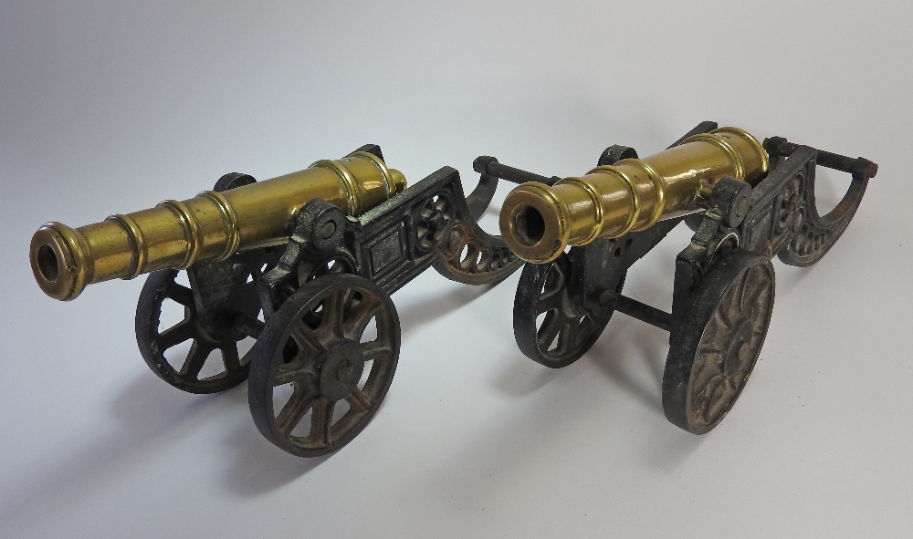 A pair of 20th century decorative small brass desk cannons on cast metal carriages,