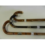 A white metal mounted walking cane together with two further wood canes