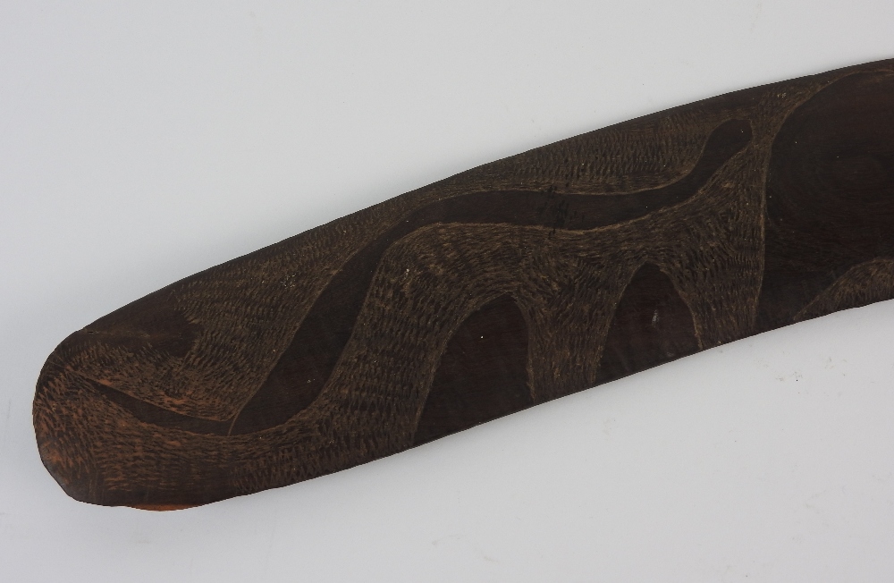 An Australian carved hard wood boomerang the decoration to one side only depicting two emus and a