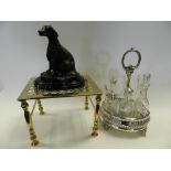 A silver plated cruet stand containing assorted glass bottles, a brass trivet stand,